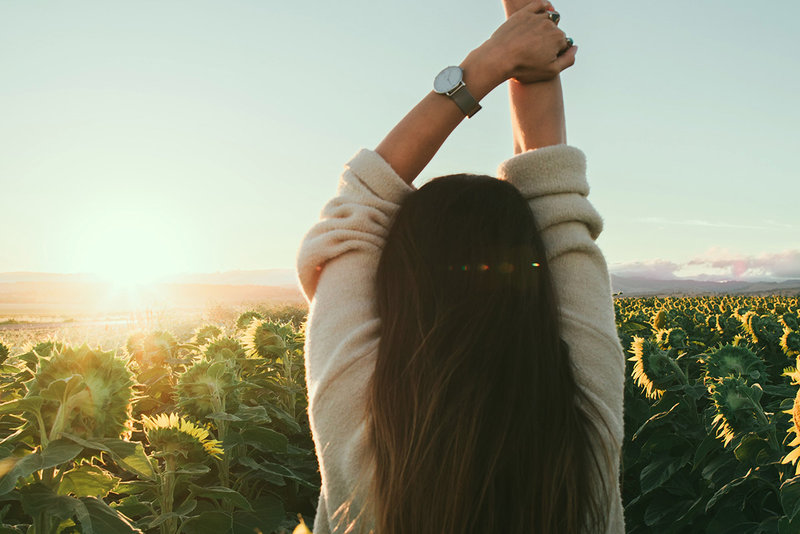 Eine Frau strengt ihre Arme entspannt in den Himmel beim WDL Dünenhof