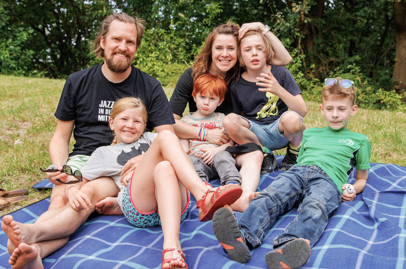 Familie lächelnd beim Familiencamp auf der Wiese beim WDL-Dünenhof