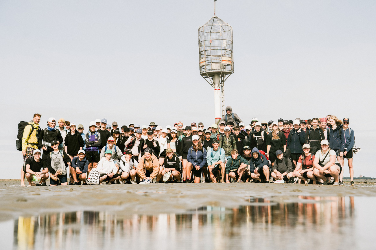 Ein lächelnde Gruppe aus Erwachsenen und Jugendlichen bei einem Ausflug ins Watt vom WDL-Dünenhof 
