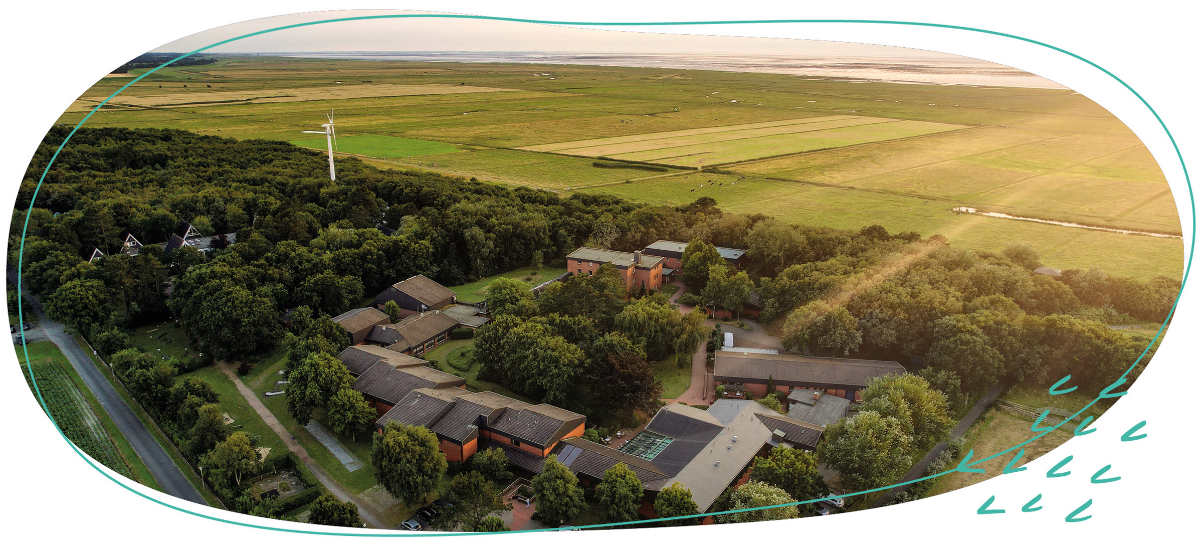 Der WDL Dünenhof mit dem Ferienhotel im Vordergrund und der Nordsee im Hintergrund ist aus der oberen Perspektive zu sehen.