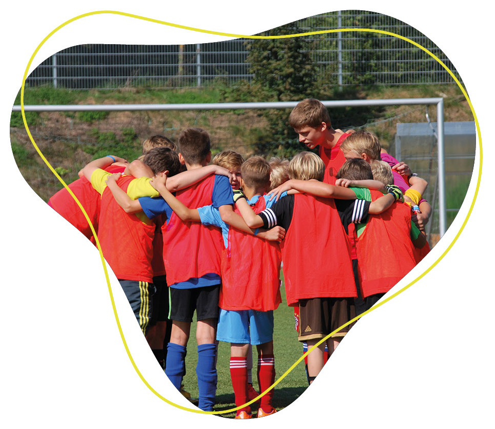 Kinder Fußballmanschaft die im Kreis stehen