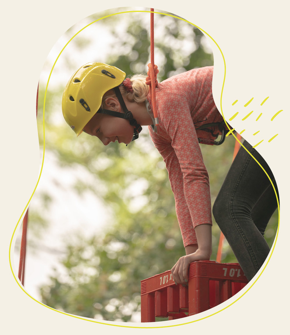 Mädchen das ein Helm träckt und gesichert ist klettert einen Turm hoch