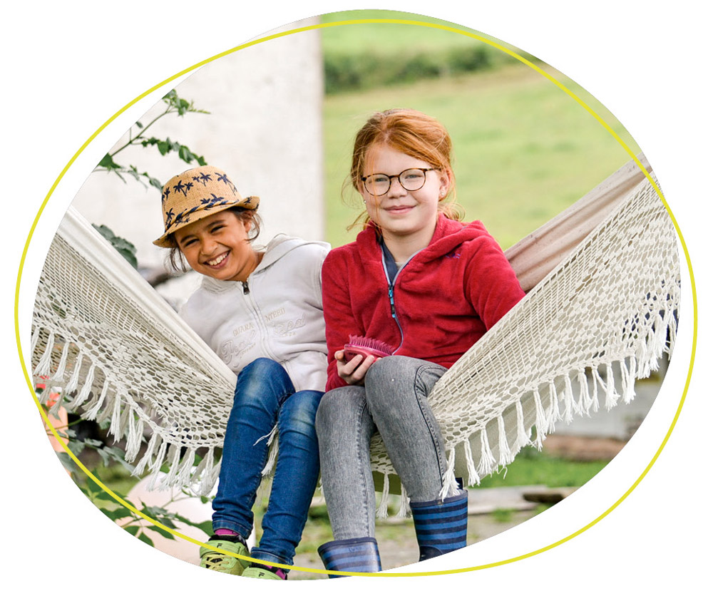 zwei Kinder sitzen in einer Hängematte 