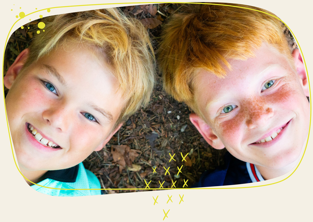 zwei Jungs liegen auf dem Boden und lächeln in die Kamera 