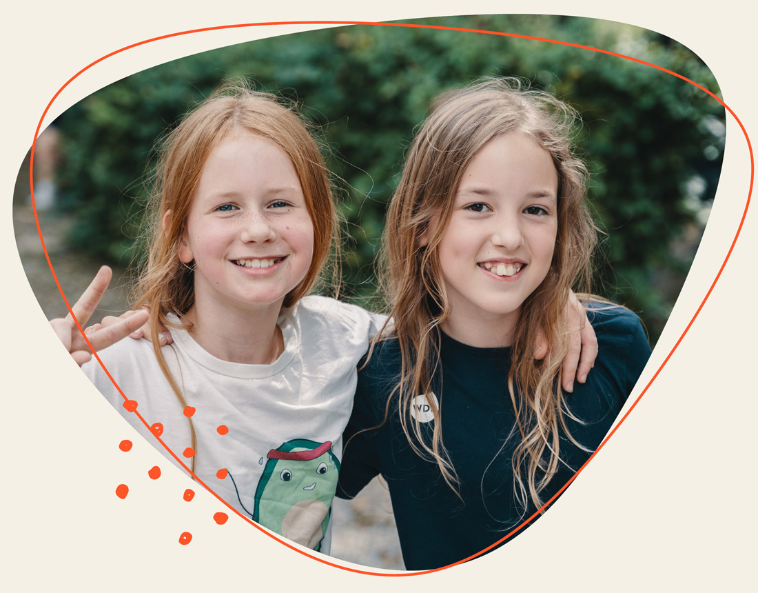 Zwei kleine Kinder um armen sich und lachen in die Kamera 