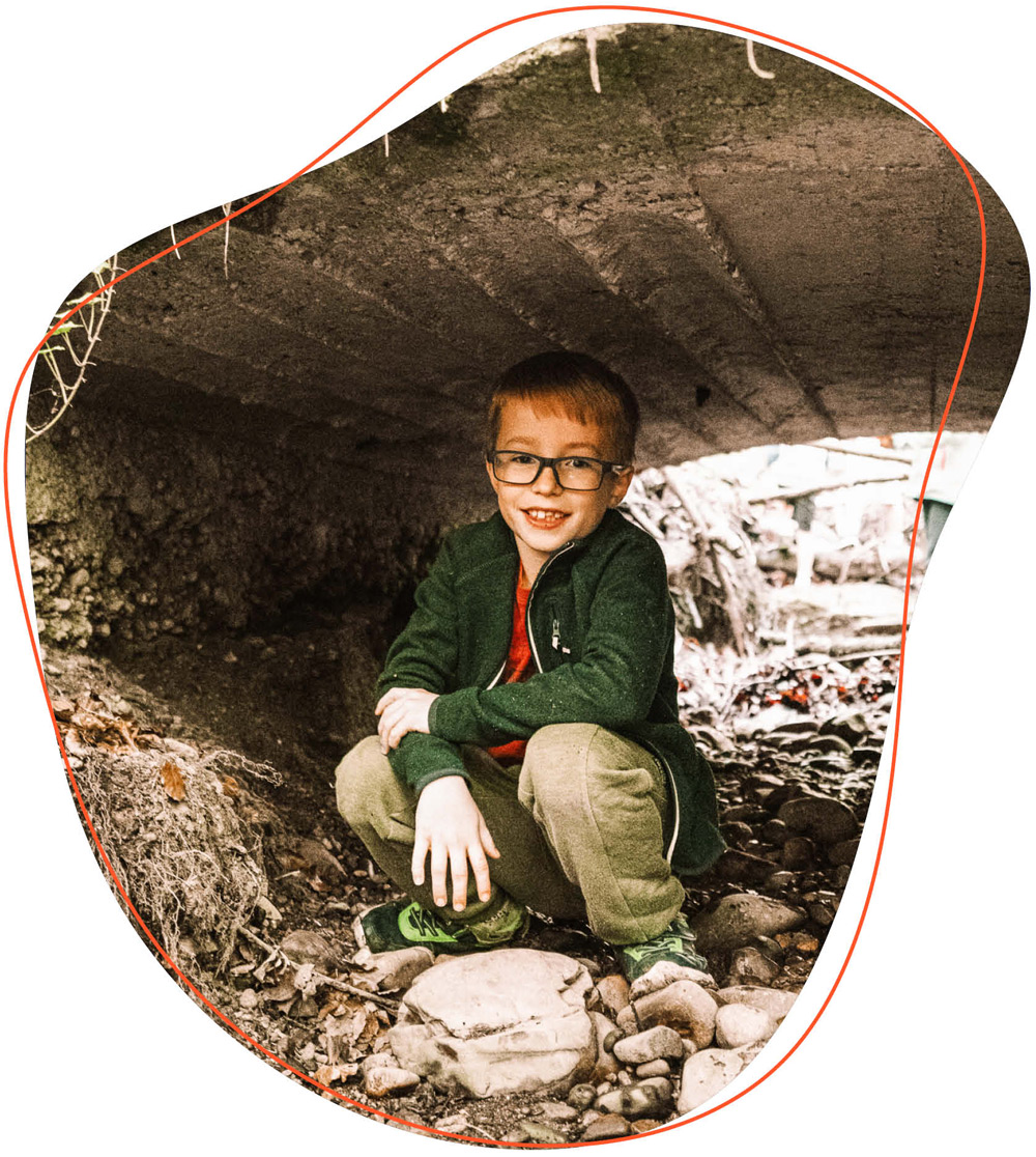 Kind sitzt unter einer Brücke 