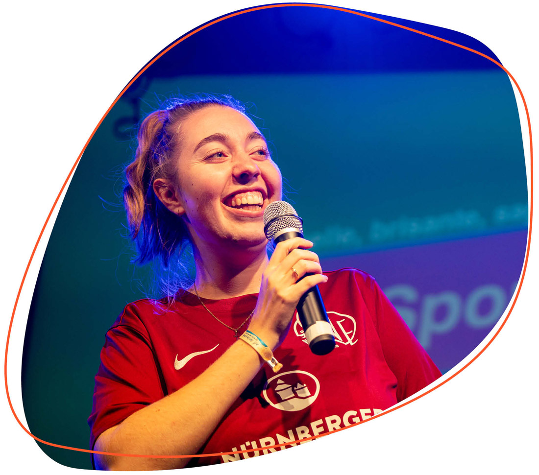 Frau auf einer Bühne mit Mikro in der Hand 