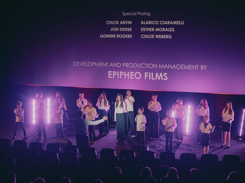 Musicals Kinder und WDL Mitarbeiter stehen im Gruppenbild vor einer Kinoleinwand